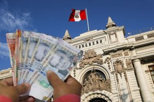 manos sosteniendo billetes frente al congreso de perú